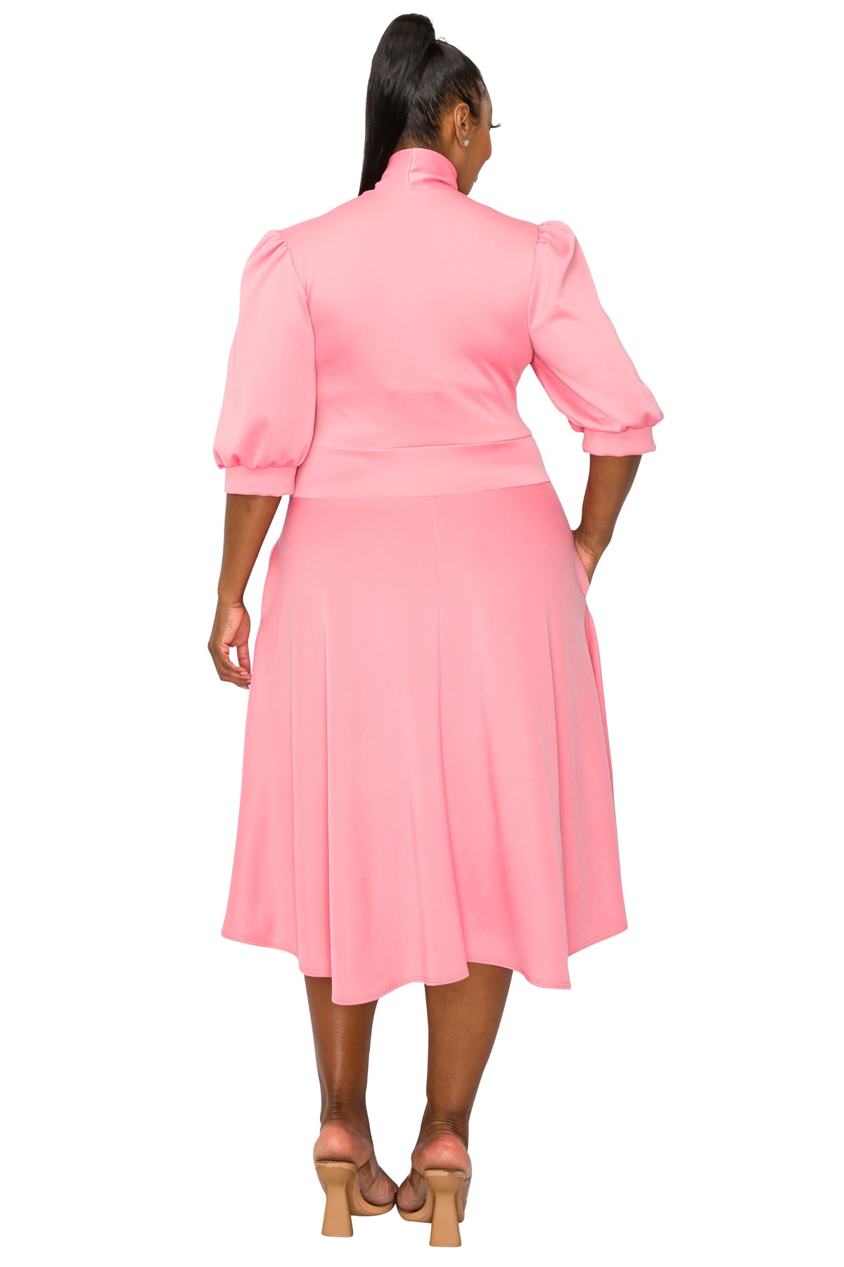 pink plus size flair dress. midi length,  hands in pockets. back view