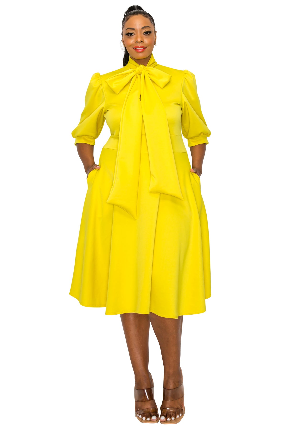 yellow plus size flair dress. midi length,  hands in pockets. front view